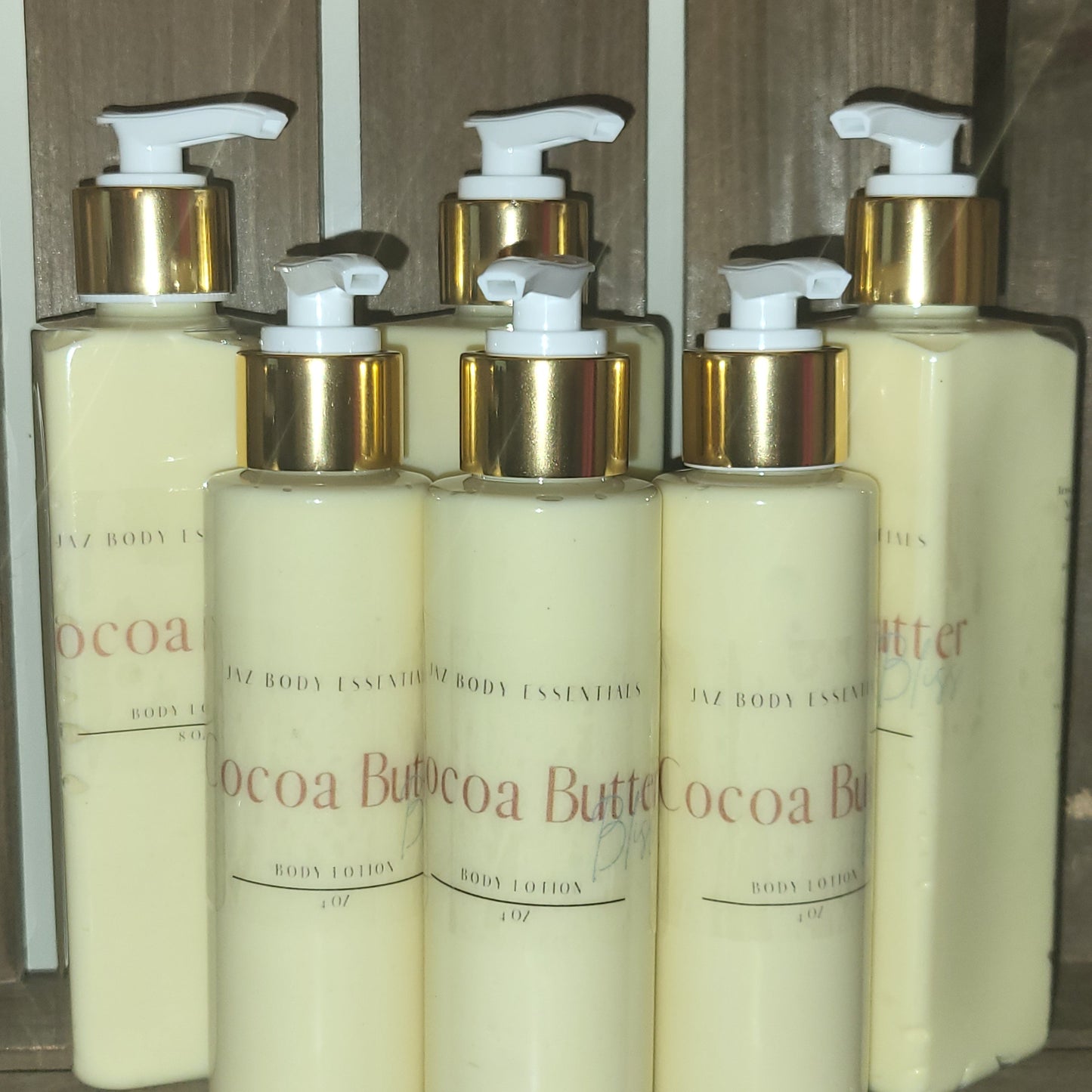 Row of Cocoa Butter body lotion bottles with gold and white pump tops.