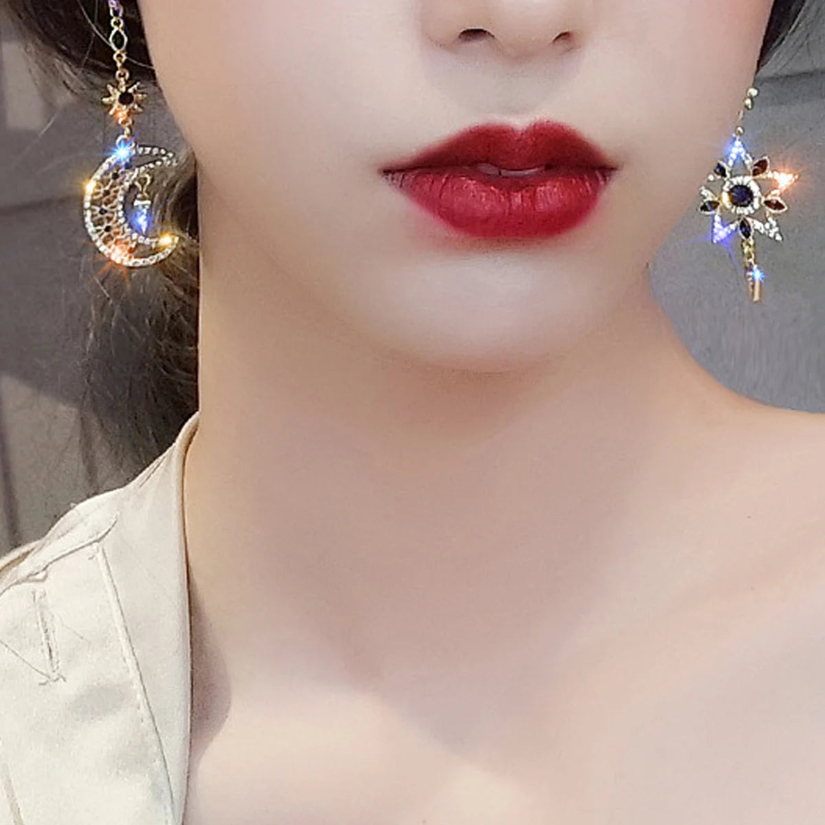 Close-up of a person wearing decorative earrings with red lipstick.