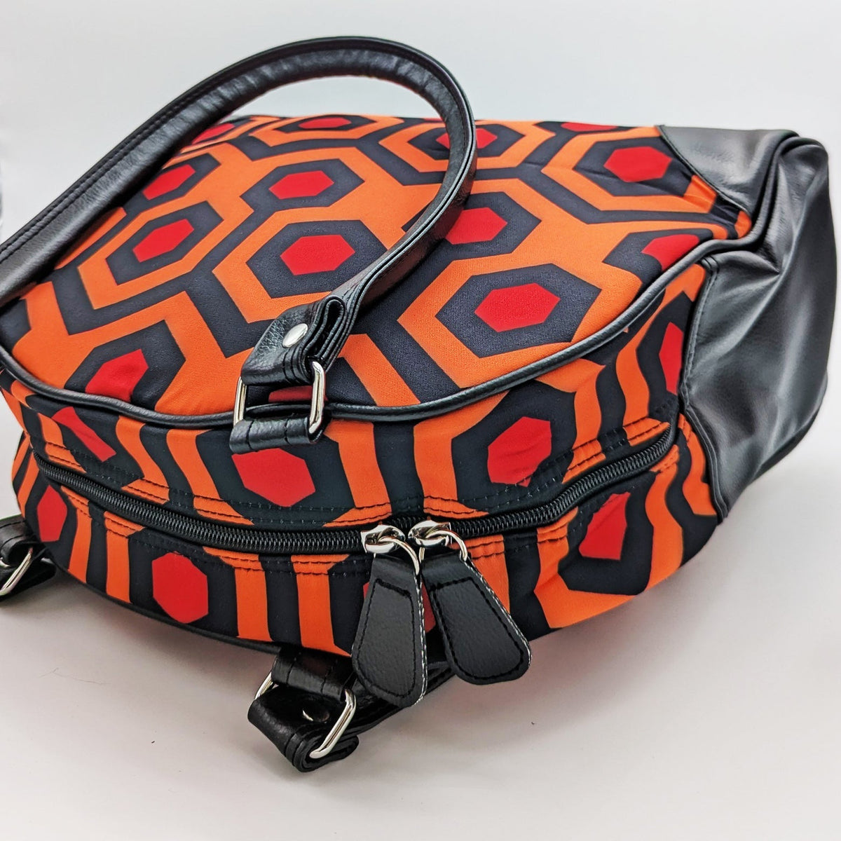 Patterned bag with orange, black, and red design on a light gray background