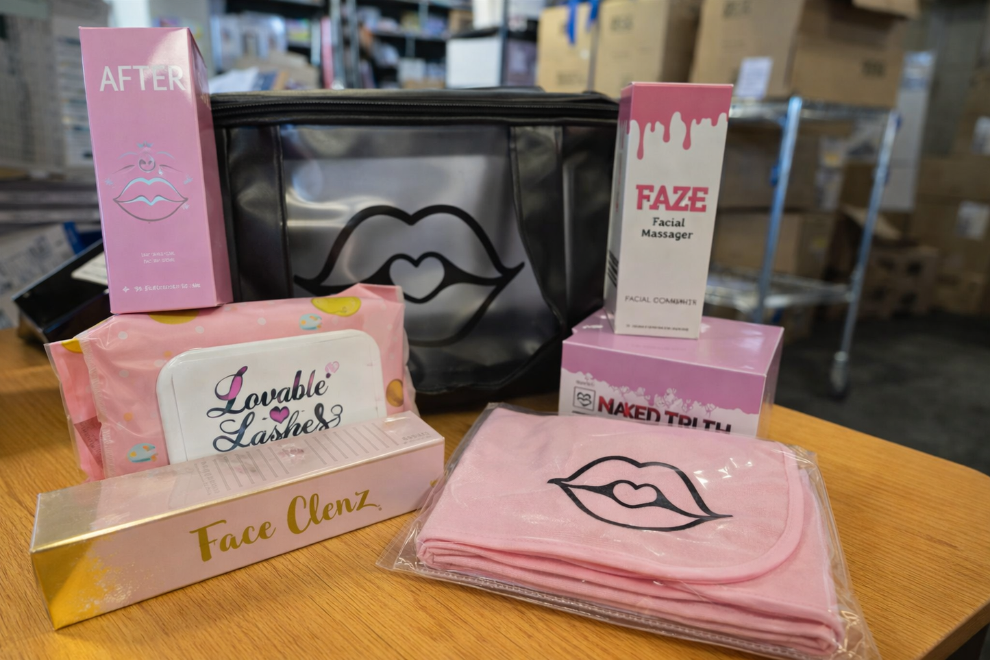 Cosmetic products including a pink face cleanser box, a black pouch with a lip design, and other beauty items on a wooden surface. Spoiled Cosmetics Skincare Bundle