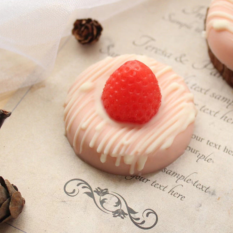 Pink dessert with a raspberry on top, placed on a textured surface with text.
