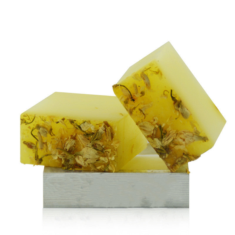 Two yellow soap bars with visible herbs on a white background