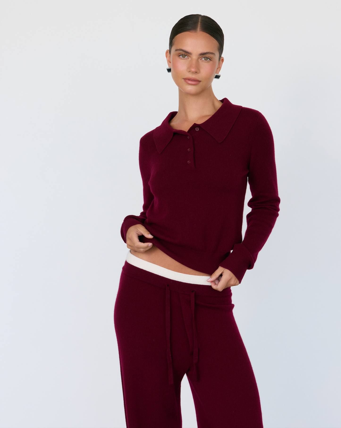 Woman wearing a burgundy Cashmere long-sleeve top and pants on a light gray background