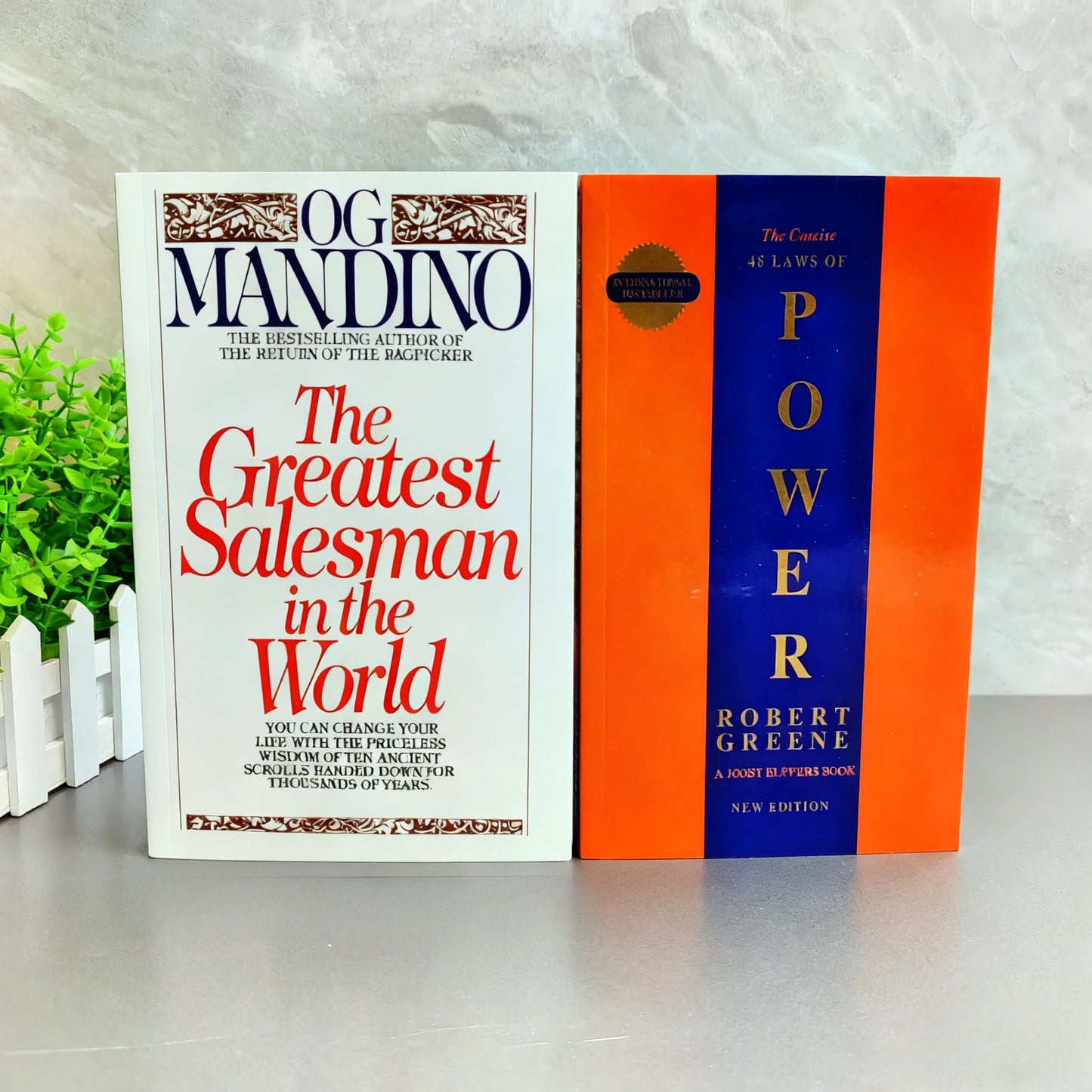 Two books titled 'The Greatest Salesman in the World' by Og Mandino and 'The 48 Laws of Power' by Robert Greene on a white surface with a light gray background.
