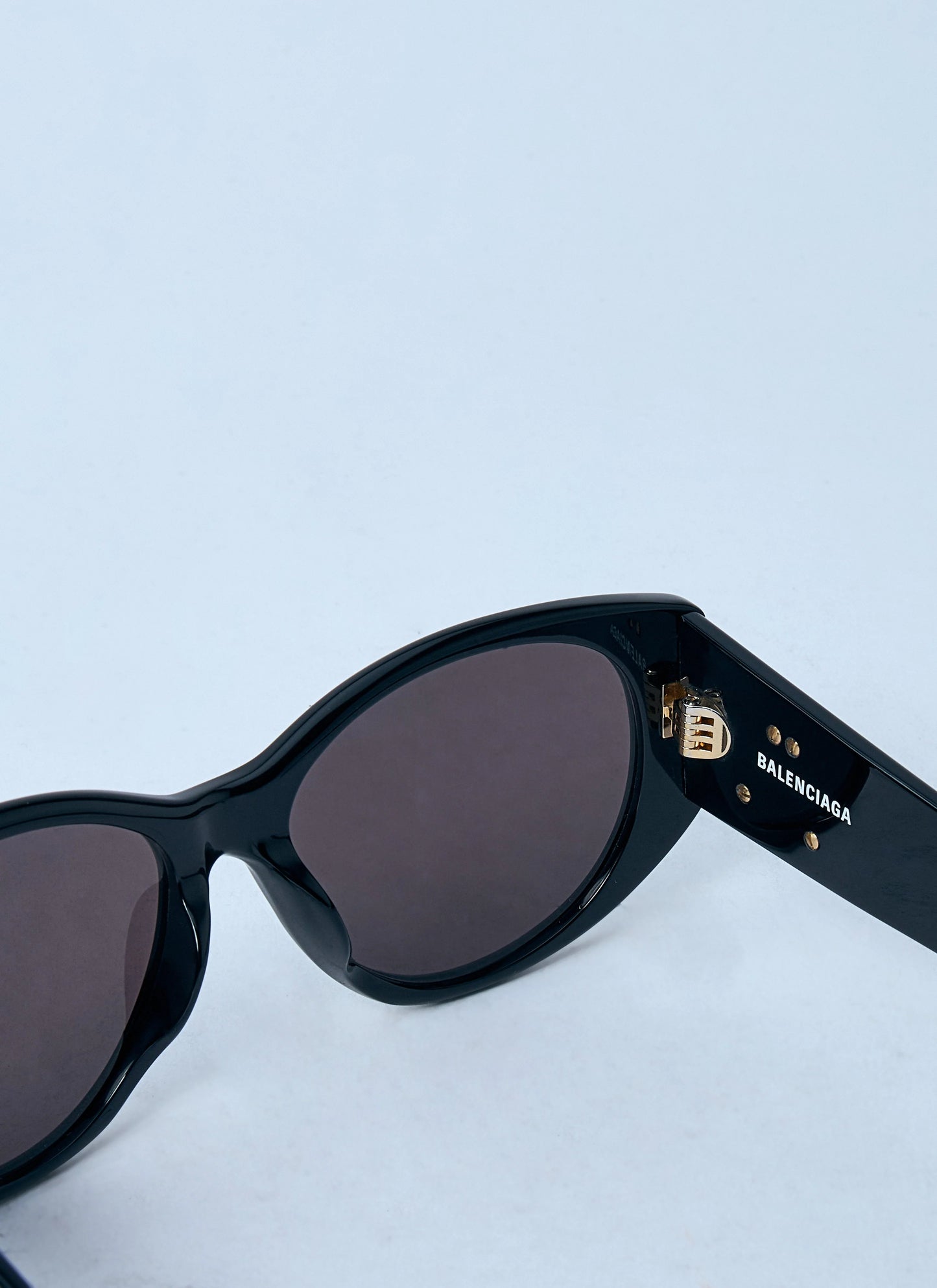 Black sunglasses with Balenciaga logo on a light blue background