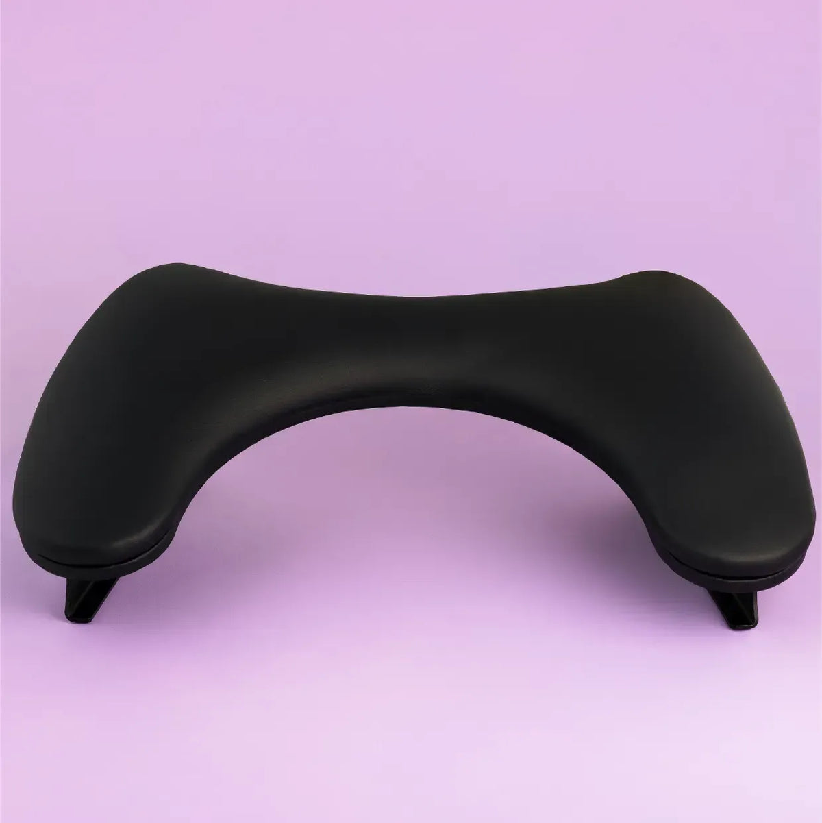 Black DNKa anatomical manicure armrest positioned against a soft, light purple background.