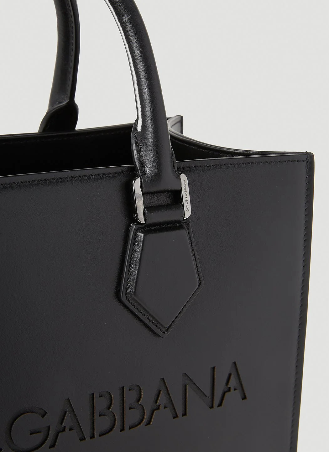 Black handbag with 'Gabbana' branding on a light gray background