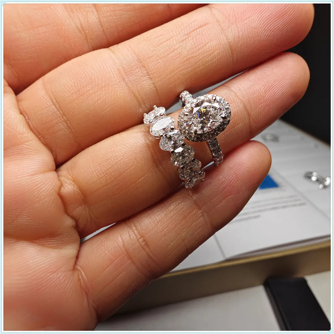 Silver ring with multiple diamonds held between fingers against a blurred background