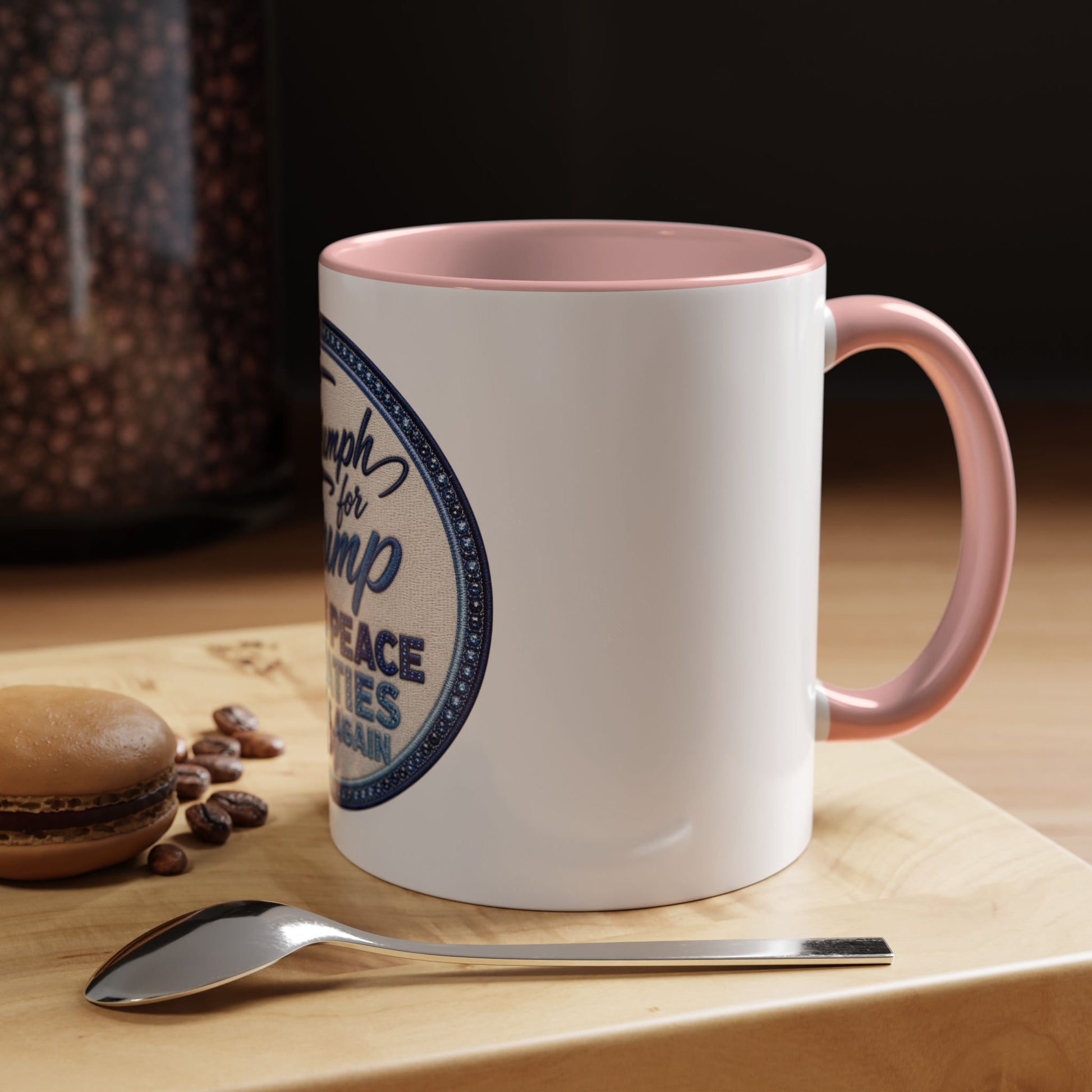 White mug with pink interior and handle on a wooden surface with coffee beans and a spoon. Donald Trump patriotic coffee cup with embroidered-style circular badge artwork for coffee and tea lovers.
