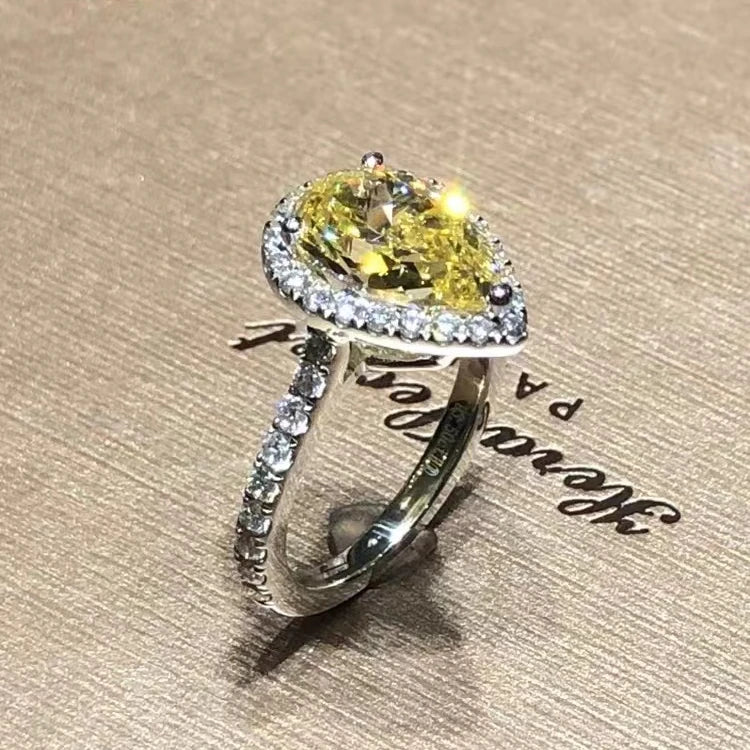 Ring with a yellow gemstone and diamond accents on a textured surface 14K White Gold with a large diamond and smaller diamonds on a textured surface Ring with a pink gemstone and diamond accents on a textured surface Ring with a yellow gemstone and diamond accents on a textured surface 14k Gold 3.5ct Moissanite Jewelry Diamond Ring A bold, architectural silhouette with a “camera-flash” kind of brilliance.  YELLOW DIAMONDS