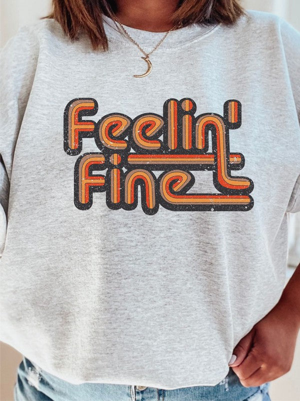 Person wearing a white sweatshirt with 'Feelin' Fine' text in orange and black.