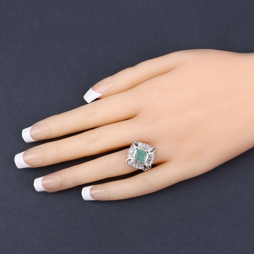 Ring with a green gemstone on a mannequin hand against a dark background
