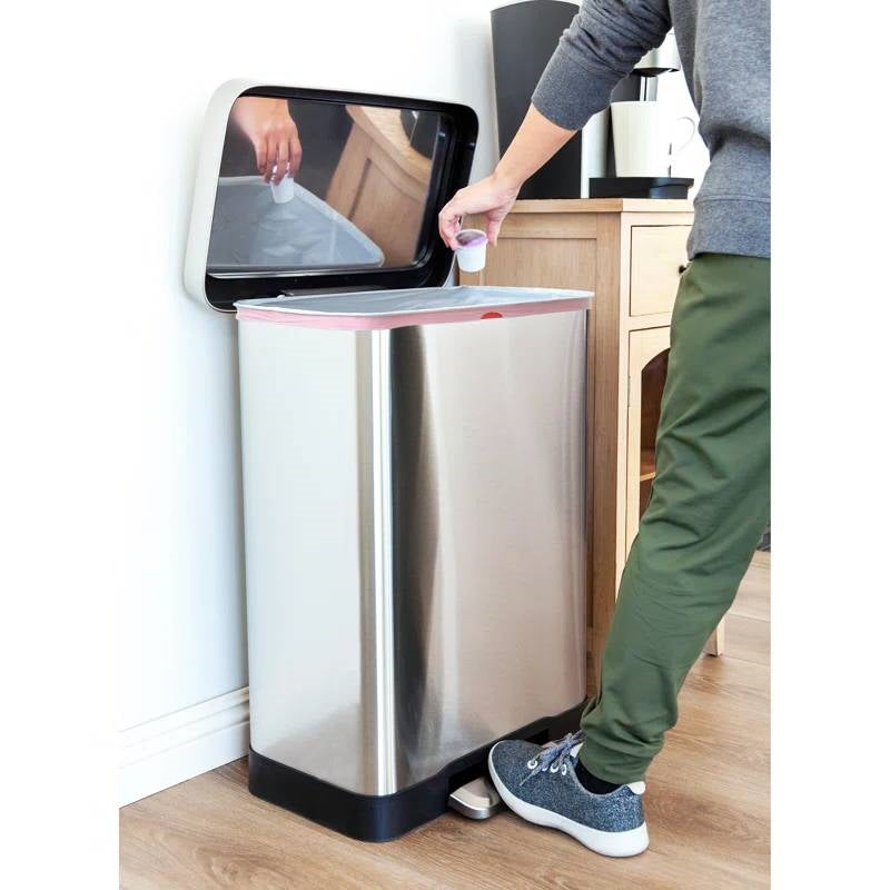 Person using a modern stainless steel trash can with a transparent liner.