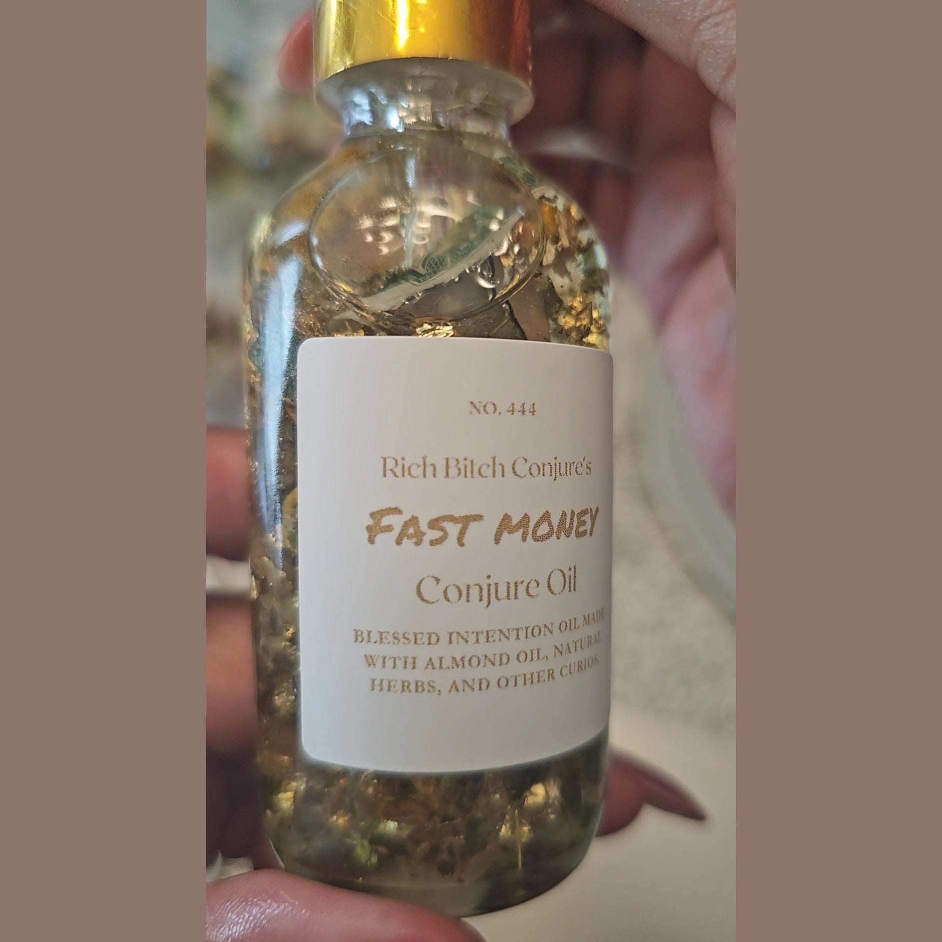 Bottle of 'Fast Money Conjure Oil' with a label held by a hand. Fast Money Oil - Luxury Hoodoo Conjure Oil for Quick Cash & Prosperity