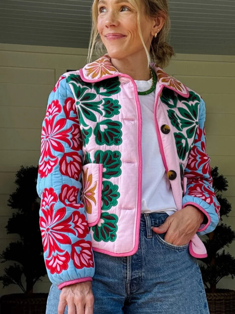 Person wearing a colorful floral-patterned jacket with a white shirt and jeans.