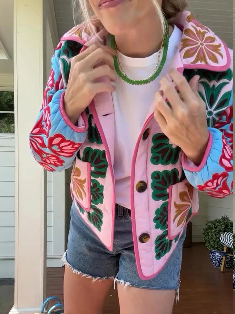 Person wearing a colorful floral jacket with a white shirt and denim shorts.