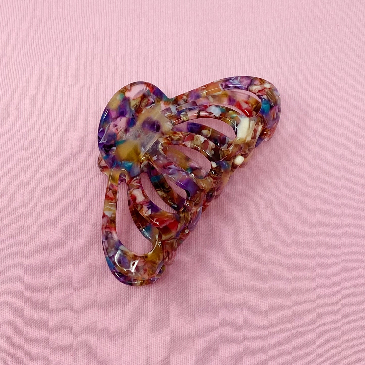 Multicolored heart-shaped hair clip on a pink background