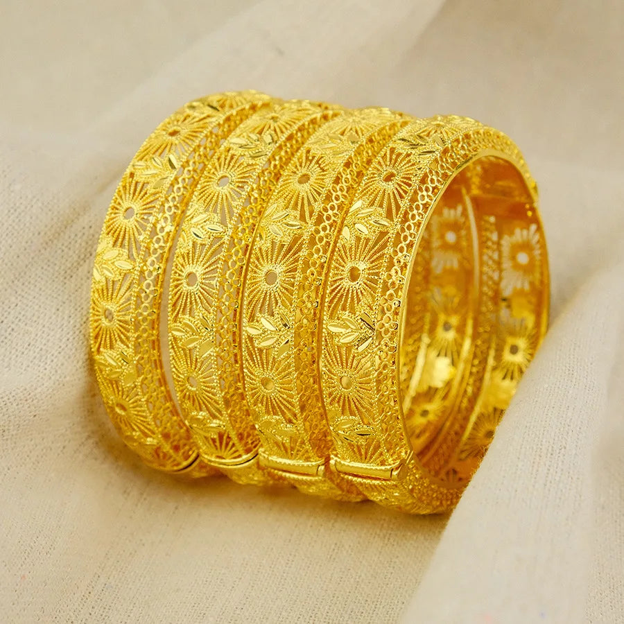 Set of gold bangles with intricate designs on a beige fabric background
