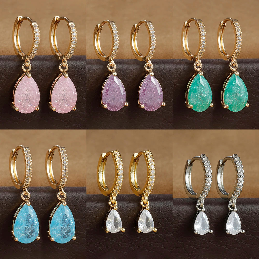 Set of gold hoop earrings with teardrop-shaped gemstones in various colors on a dark surface.