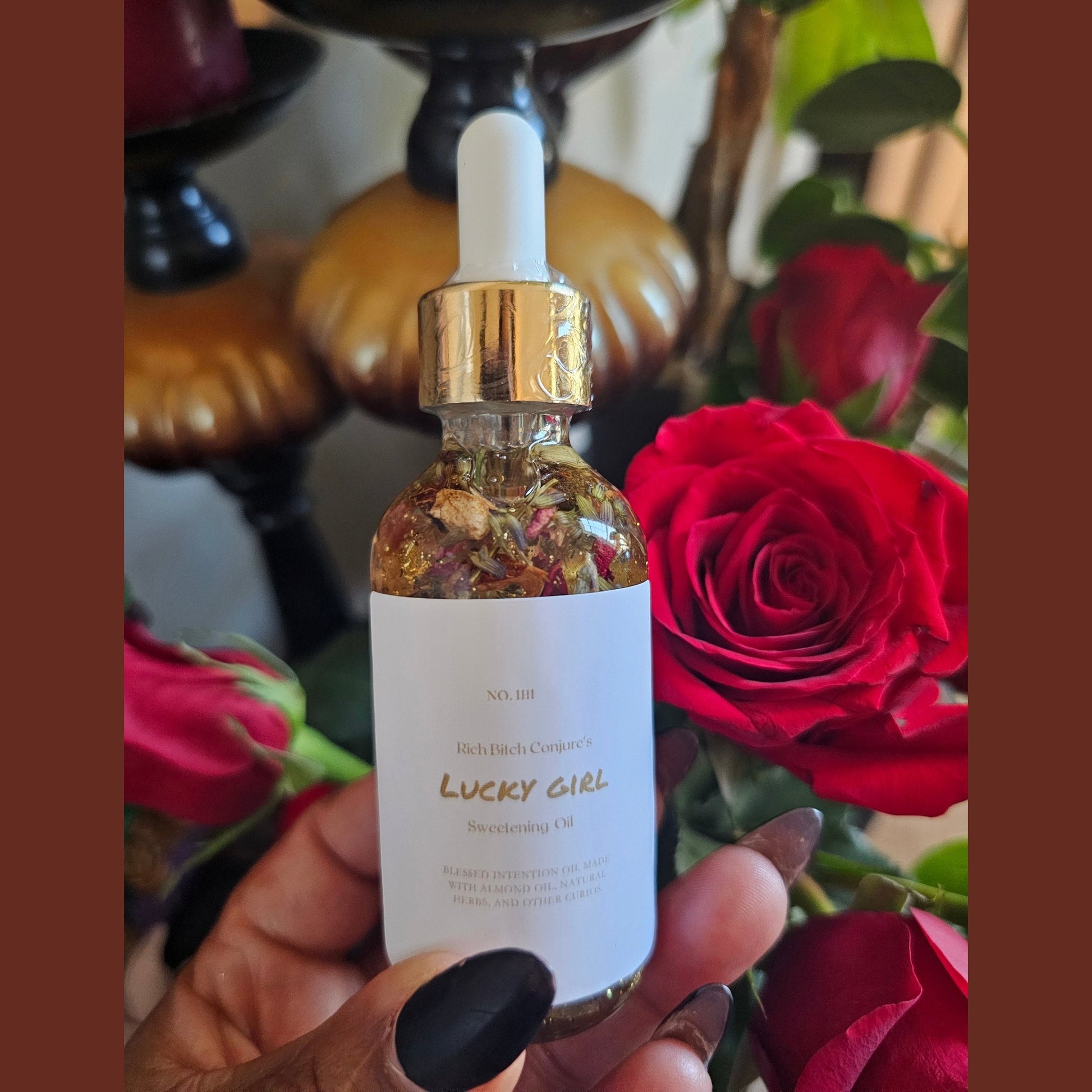 Bottle of 'Lucky Girl' product held in front of red roses. Lucky Rich Girl Hoodoo Conjure Oil | Wealth, Beauty, Glamour & Good Fortune Conjure Oil | Limited Edition