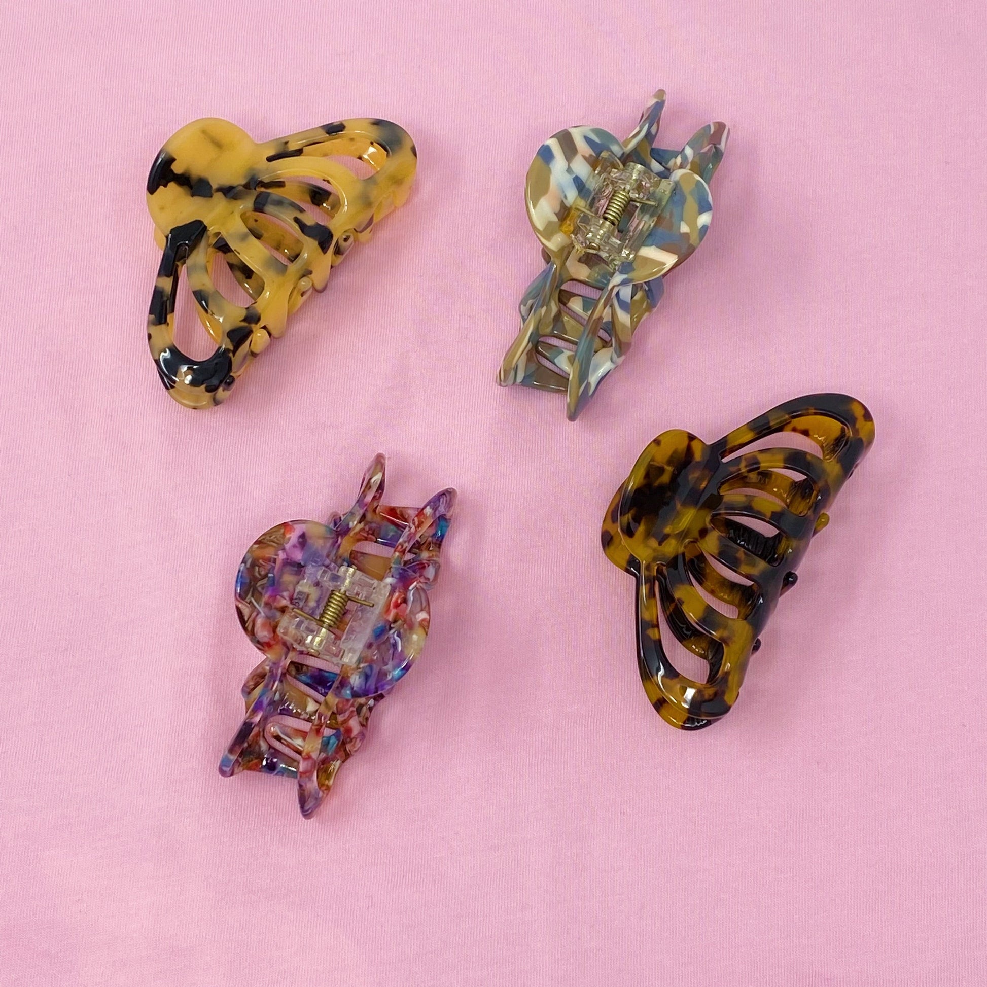 Four colorful hair clips on a pink background