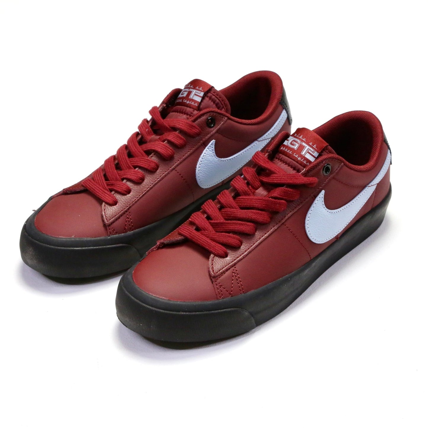 A pair of Nike low-top sneakers in a dark red colorway, featuring a white Swoosh logo and black soles, photographed on a clean white background. Nike SB Blazer Low Pro GT DV1226-600