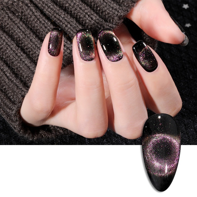 Close-up of a hand showcasing a vibrant black and purple cat-eye magnetic glitter nail polish, set against a stylish, textured background.