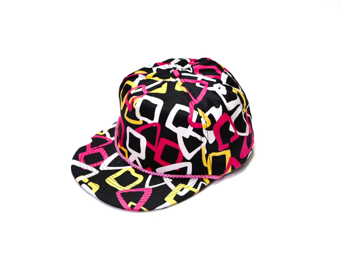 A black baseball cap with a vibrant geometric pattern in pink, yellow, and white, featuring a thin pink rope detail across the front band, set against a plain white background.