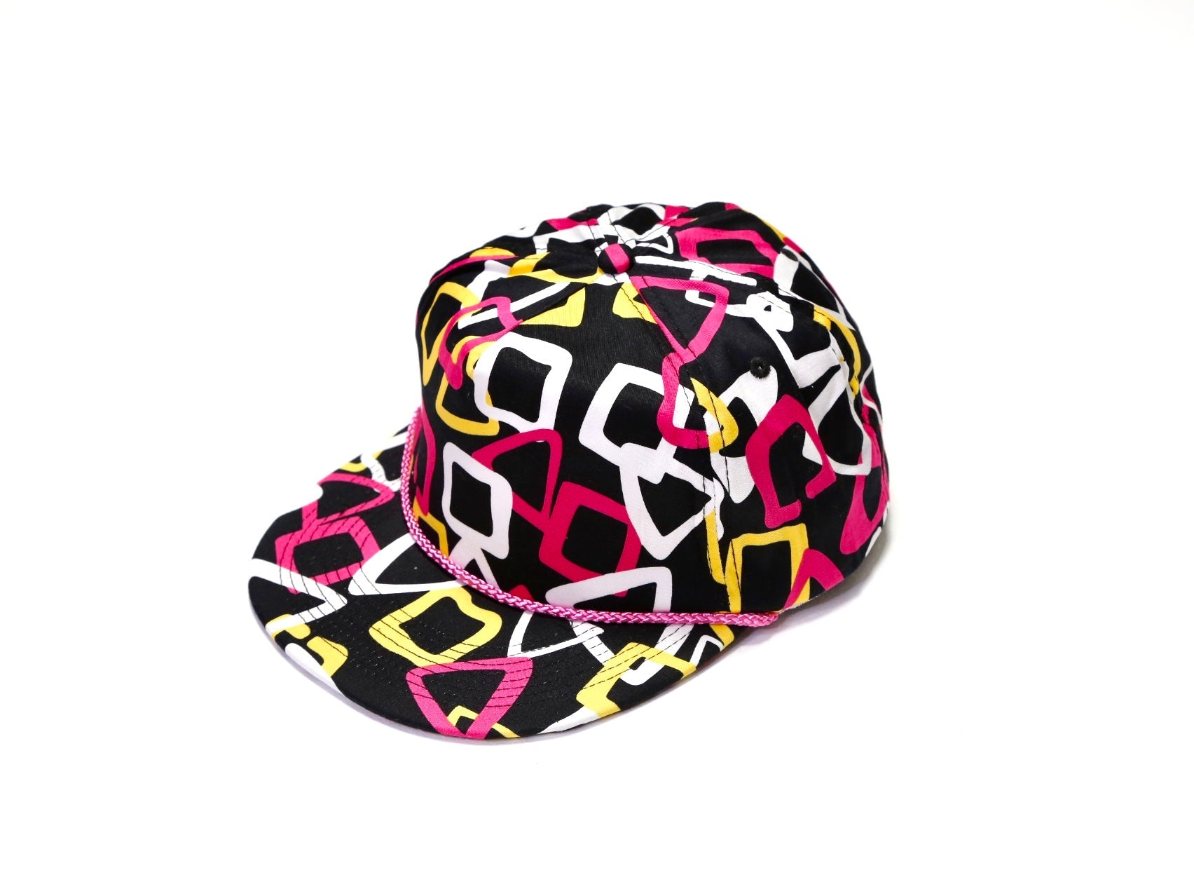 A black baseball cap with a vibrant geometric pattern in pink, yellow, and white, featuring a thin pink rope detail across the front band, set against a plain white background.