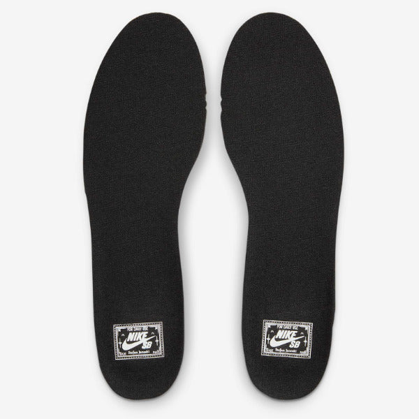 A pair of black Nike shoe insoles shown from the top on a light gray background, each featuring a white Nike Swoosh 3D logo patch near the heel. Nike SB Janoski Black White