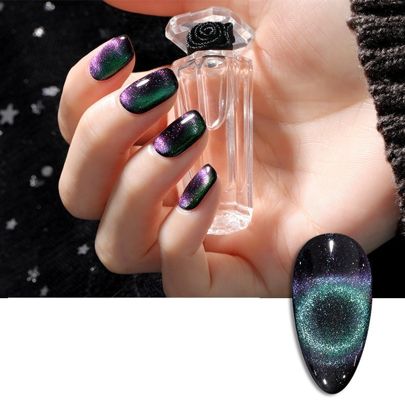 A hand showcasing intricate galaxy-themed nail art, delicately holding a clear bottle of cat eye nail polish.