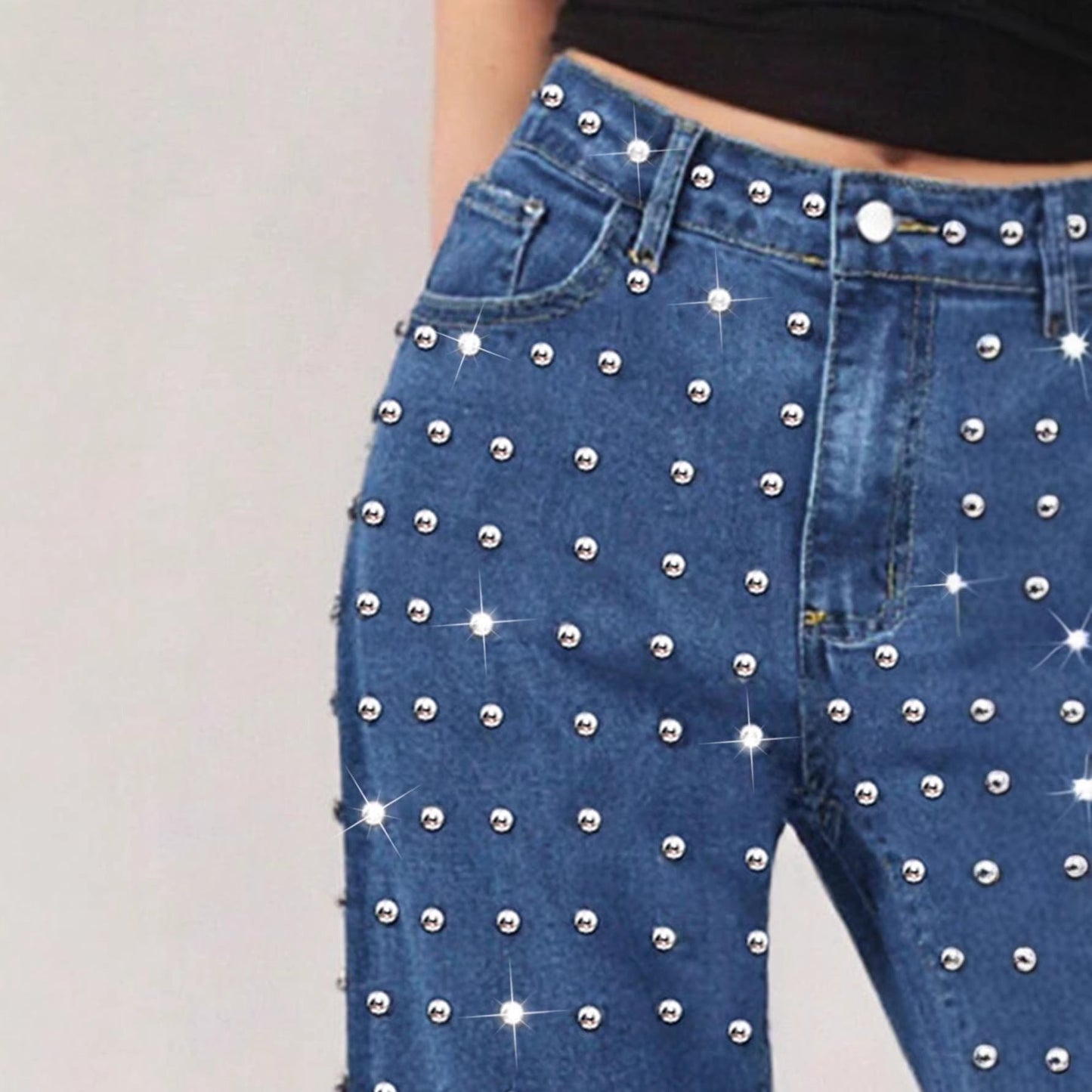 Blue jeans with silver studs on a plain background