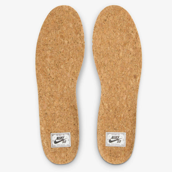 A pair of natural cork shoe insoles shown from the bottom on a light gray background, each with a white Nike Sock label near the heel. Nike SB Janoski Black White