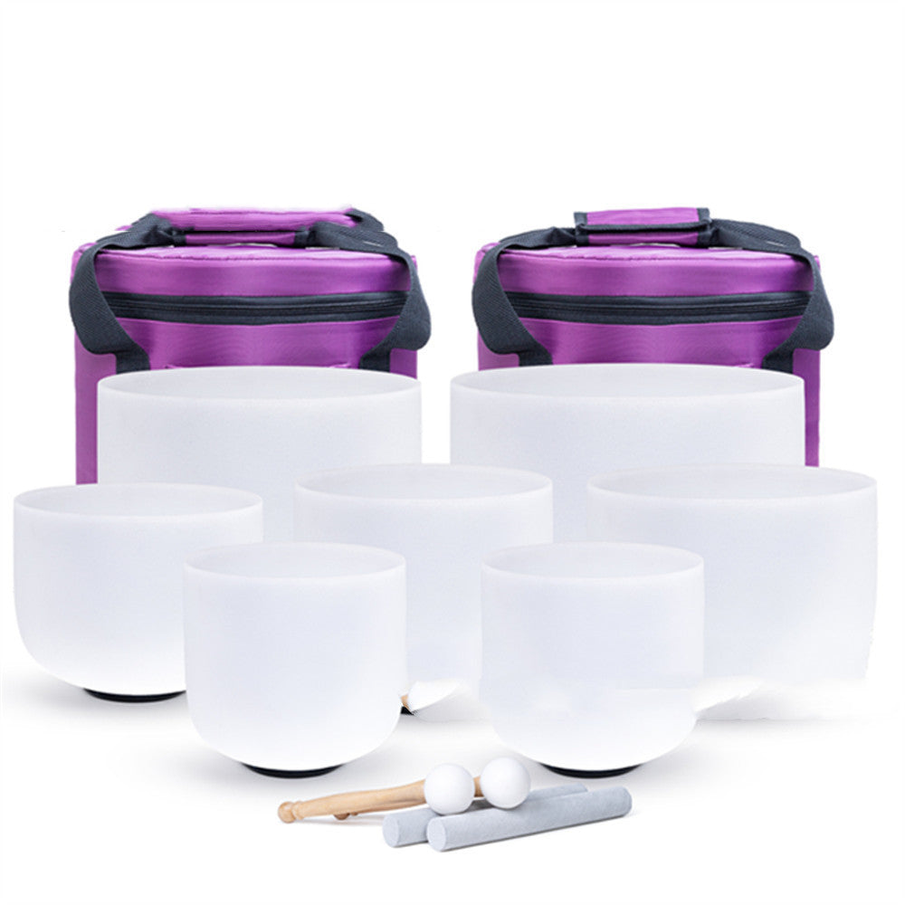 Set of white singing bowls with purple carrying cases on a white background