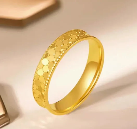 Gold ring with textured design on a beige background