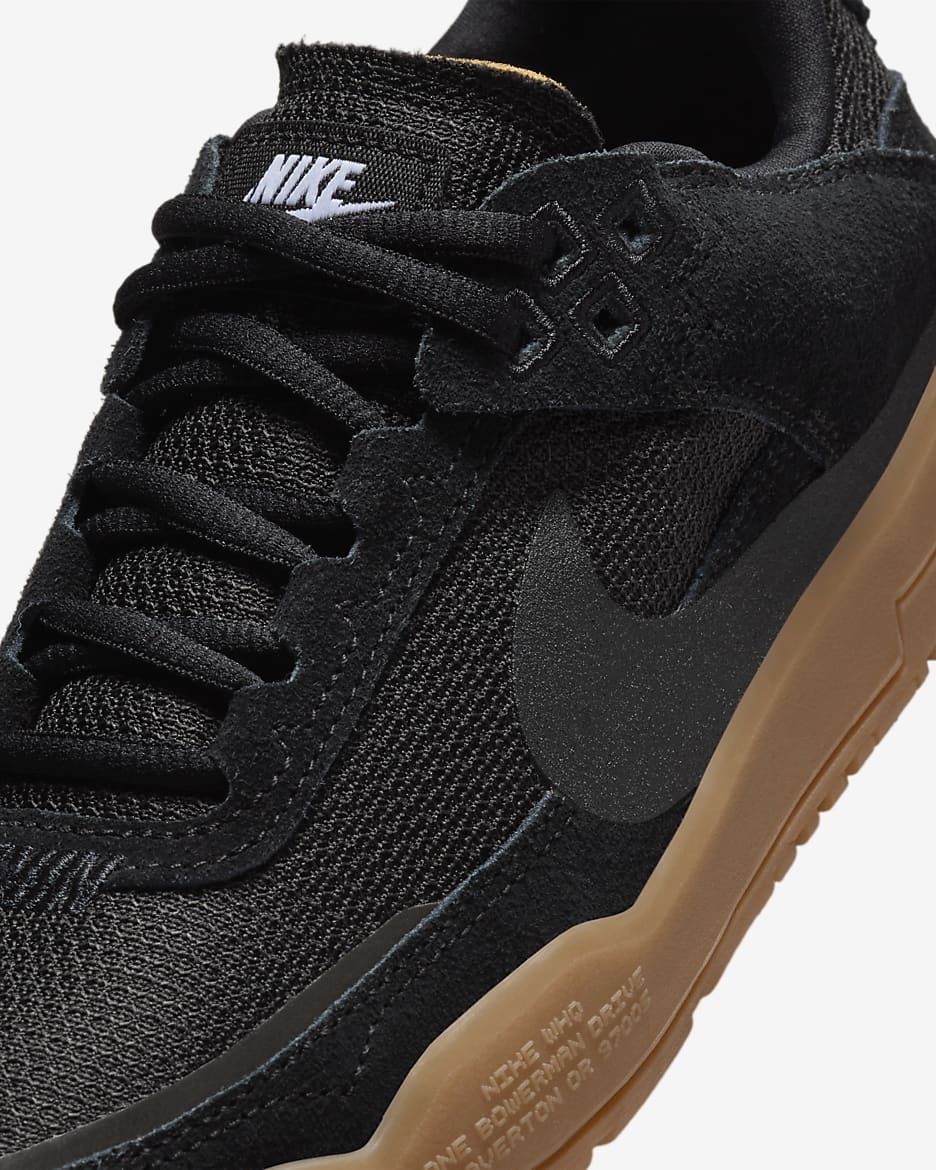 Close-up of a Nike sneaker in black with a gum brown sole, showing the textured mesh and suede upper, black laces, and a white Nike logo on the tongue. Nike SB Day One - Youth - FN4210-001
