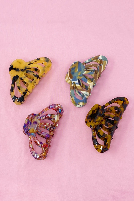 Four colorful butterfly-shaped hair clips on a pink background