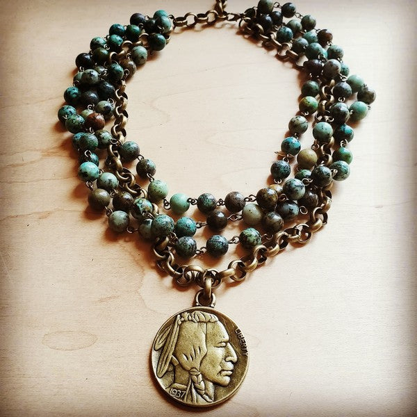 African Turquoise Collar Length Necklace with Indian Head Coin Elevate your necklace game with this stunning African turquoise and antique gold collar that doubles as the perfect layering piece. Genuine African turquoise stones catch the light beautifully, while an authentic Indian head coin adds vintage charm and character. At 18 inches with a 2.5-inch extender, this choker-length necklace transitions effortlessly from solo statement to layered masterpiece. Whether you're channeling boho vibes or mixing 