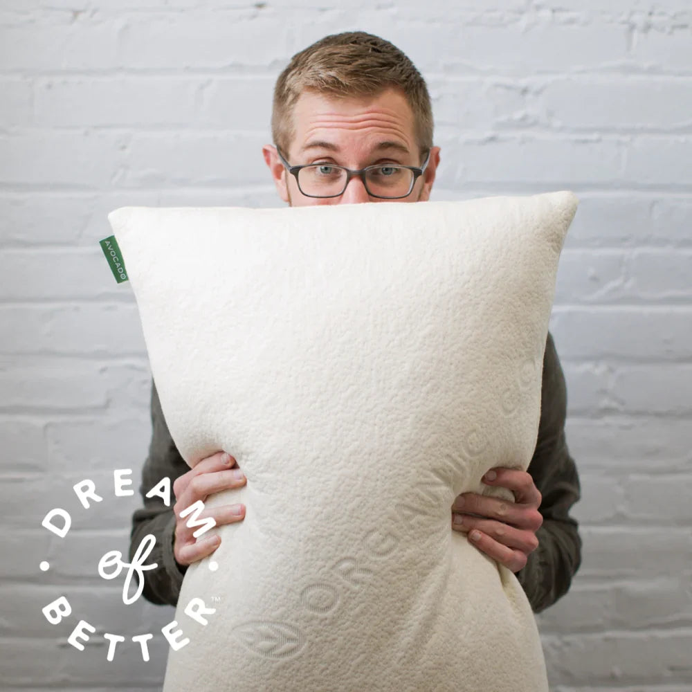 Man holding a large organic material  against a gray brick wall.