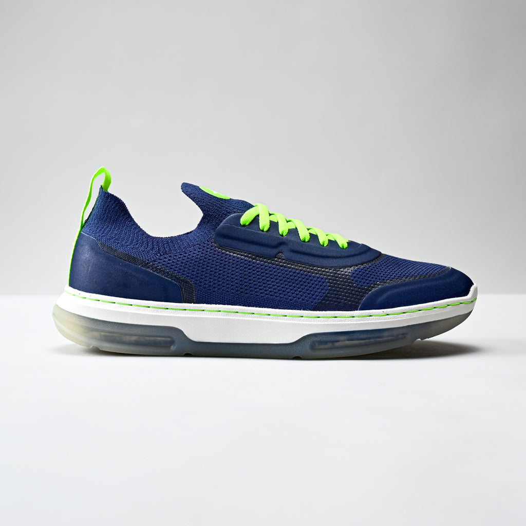 Blue athletic shoe with green accents on a gray background