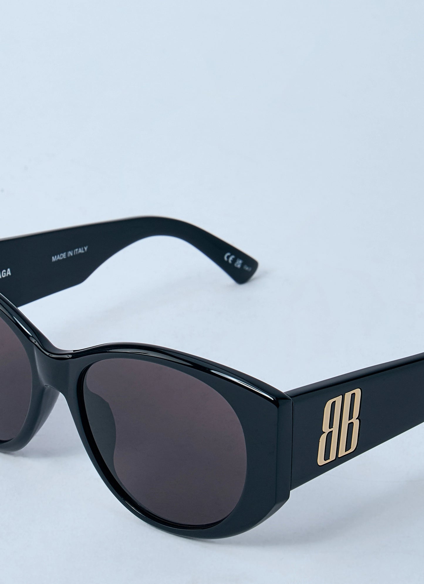 Black sunglasses with gold logo on a light blue background
