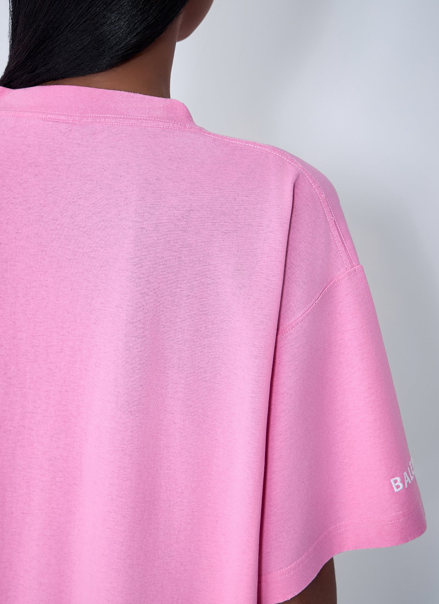 Pink t-shirt with a brand logo on a plain background