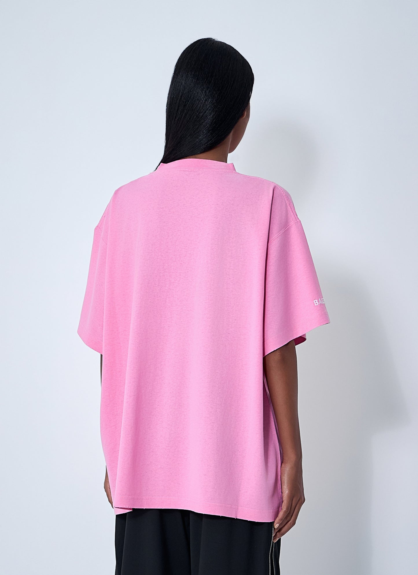 Person wearing a pink oversized shirt with a white background