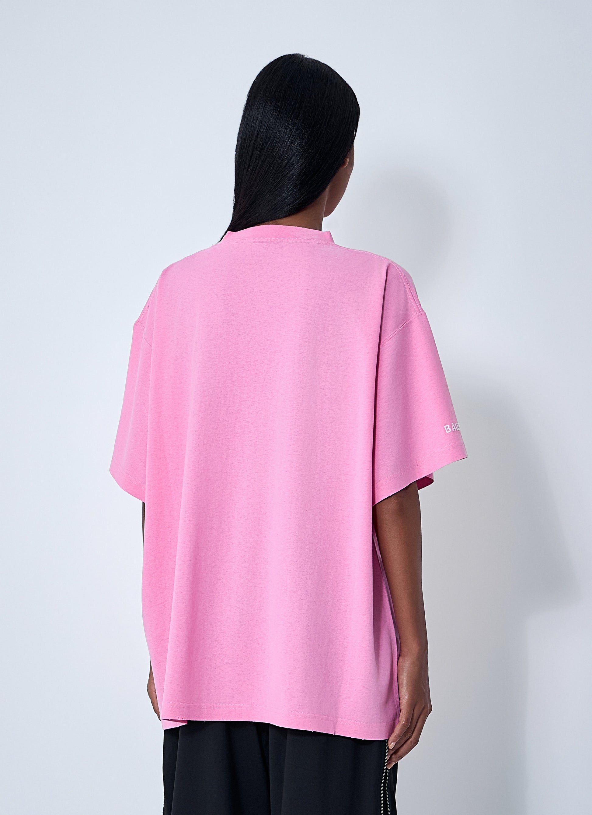Person wearing a pink oversized shirt with a white background