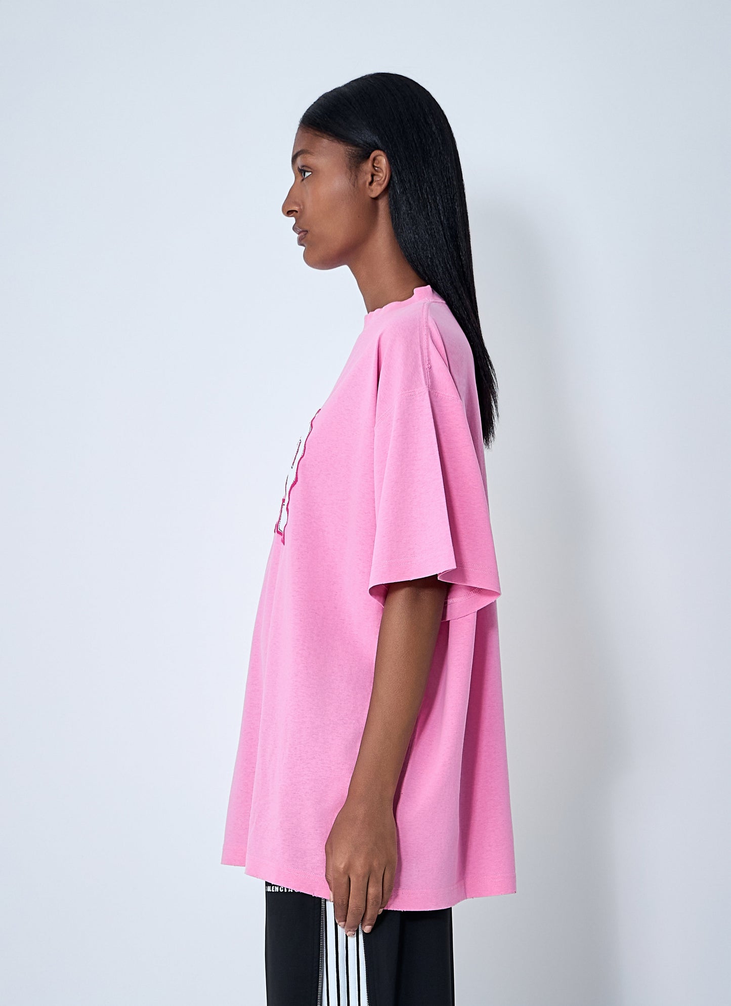 Person wearing a pink oversized t-shirt against a white background
