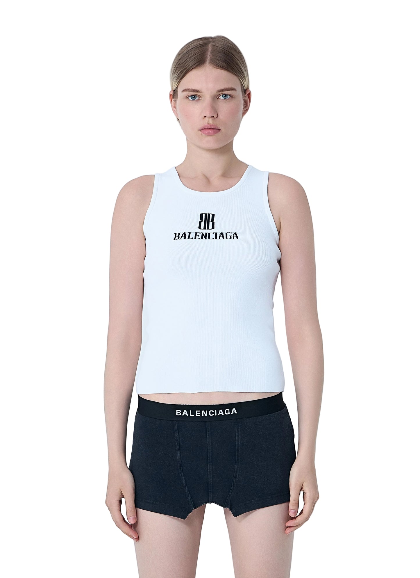 Person wearing a white tank top and black shorts with Balenciaga branding on a light gray background