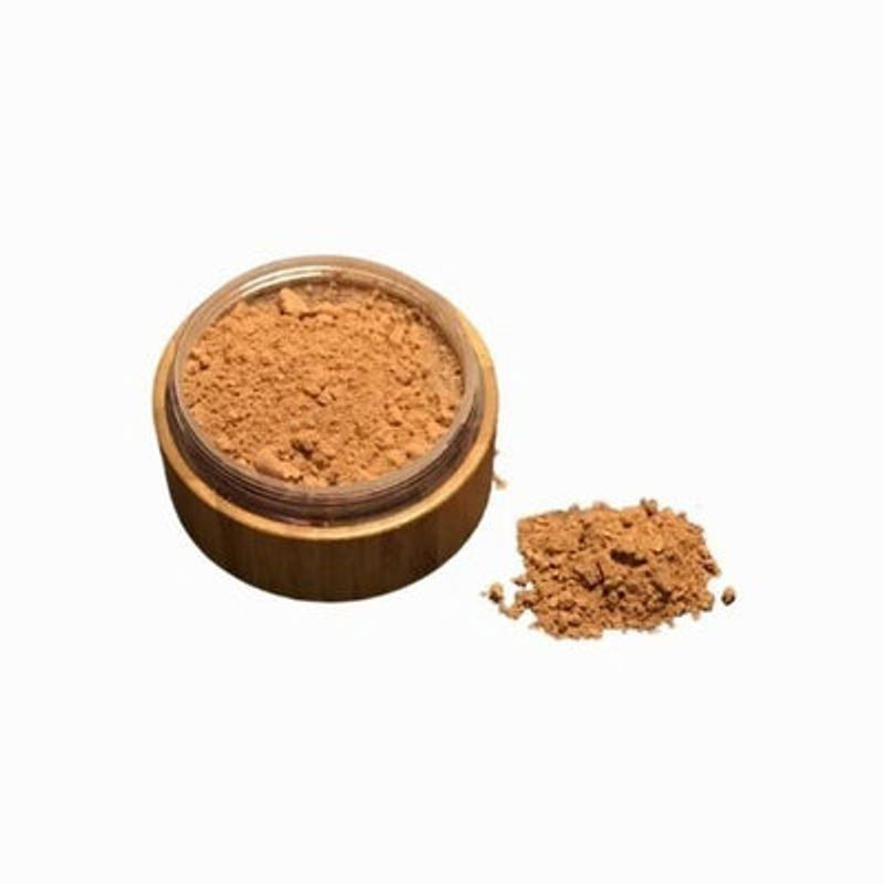 Brown powder in a small open container on a white background