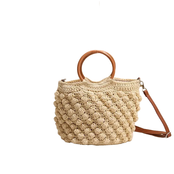 Beige woven handbag with wooden handles on a light surface.