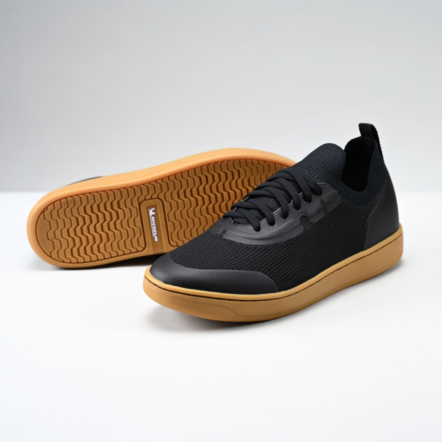 Black sneakers with brown soles on a light gray background