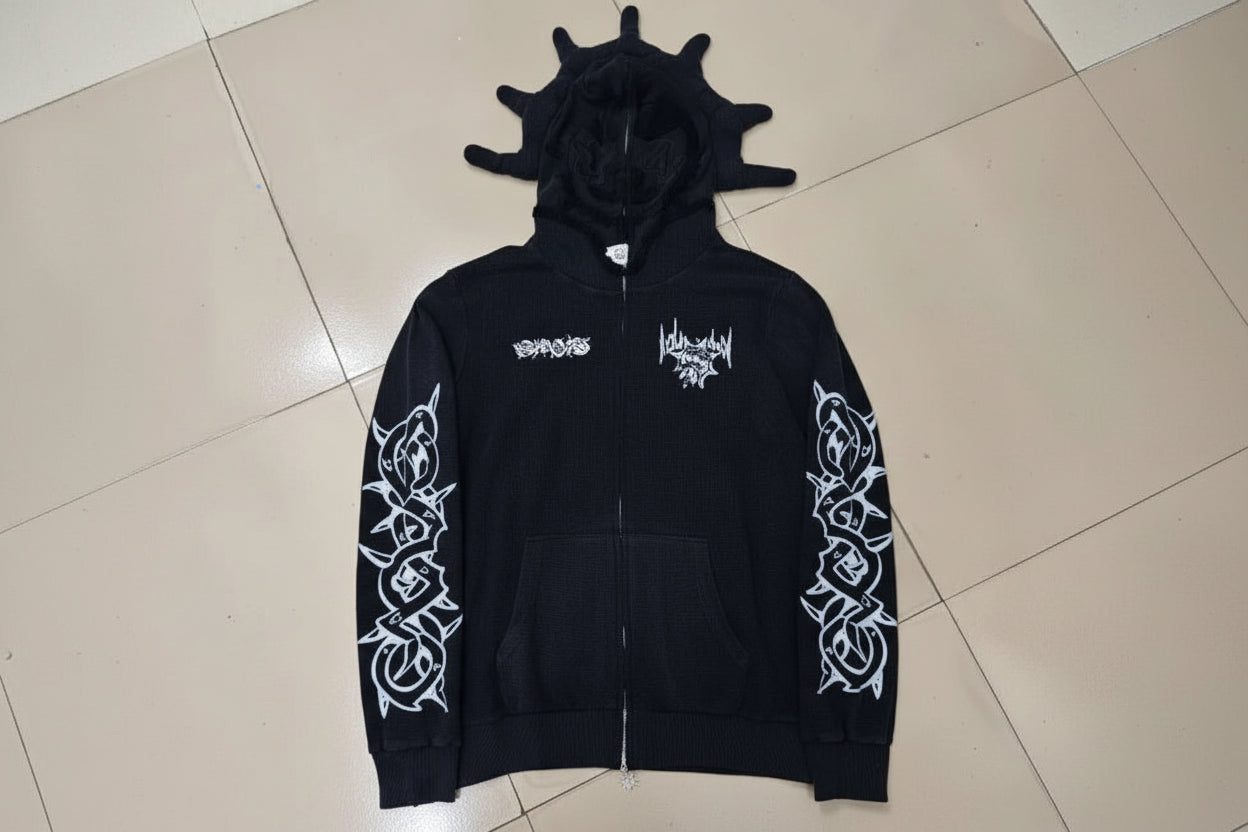 Black hoodie with white graphics and text on a tiled floor